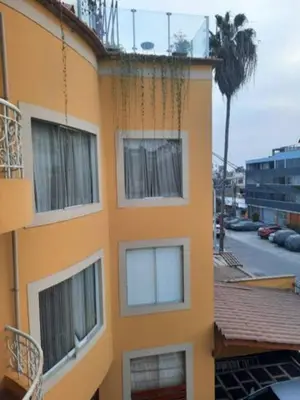 a yellow building with white windows and a palm tree at Loft abierto y moderno & Aire acondicionado in Lima
