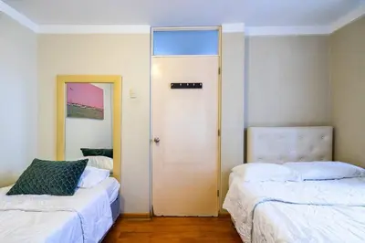 a room with two beds and a door with a mirror at Balconcito Peruano & AMPLIO 2 dormitorios in Lima