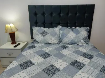 a blue and white quilt on a bed with a lamp at Casa Amarello in Lima