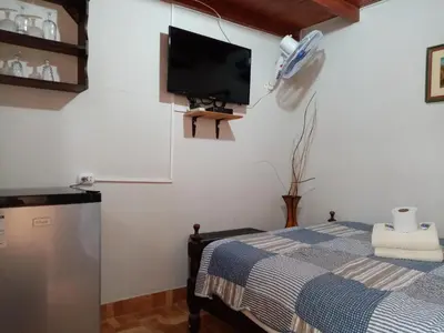 a bedroom with a bed and a tv on the wall at La Casa Maruja Habitación doble P in San Bartolo
