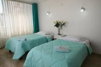 two beds in a room with green comforter at El Gamonal - Paracas in Paracas