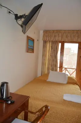 a bedroom with a bed and a desk and a window at Hotel Los Flamencos in Paracas