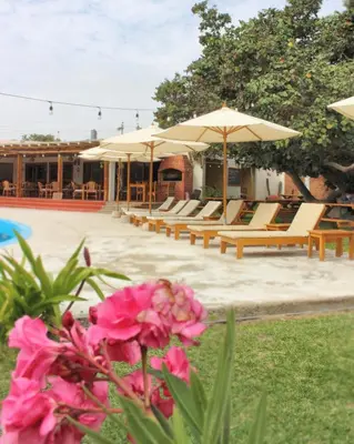 a group of lounge chairs and umbrellas next to a pool at Hotel El Condor in Paracas