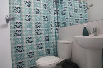 a bathroom with a toilet and a sink and a shower curtain at Qurpawasi in Lima