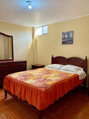 a bedroom with a bed with an orange blanket at Hospedaje Anais in Pisco