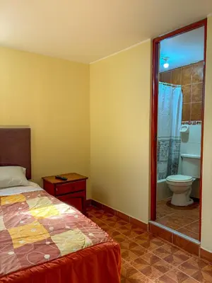 a bedroom with a bed and a bathroom with a toilet at Hospedaje Anais in Pisco