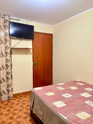 a room with a bed and a flat screen tv at Hospedaje Anais in Pisco