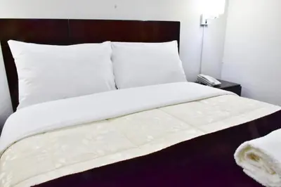 a bed with white sheets and pillows in a room at KASAS DEL INKA MACHUPICCHU in Machu Picchu