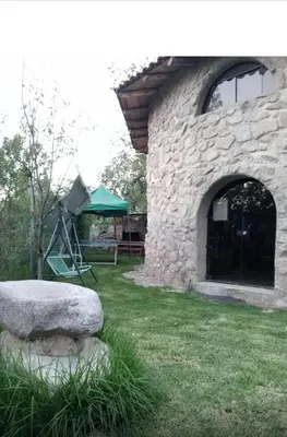 a stone building with a playground in a yard at Illa Wasi Sacred Valley in Urubamba
