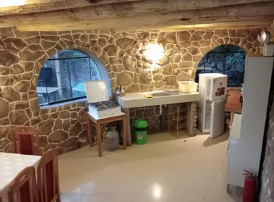 a kitchen with a stone wall with a sink and a refrigerator at Illa Wasi Sacred Valley in Urubamba