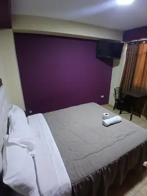 a bedroom with a large bed with a purple wall at Hotel Residencial San Isidro in Hualmay