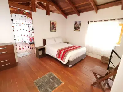 a bedroom with a bed and a wooden floor at APARMENT SAMANA HOUSE OLLANTAYTAMBO in Ollantaytambo