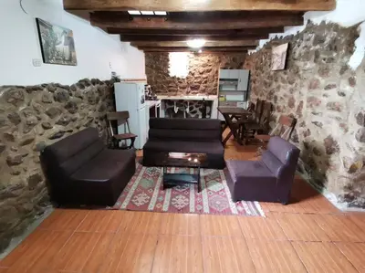 a living room with leather furniture and a stone wall at APARMENT SAMANA HOUSE OLLANTAYTAMBO in Ollantaytambo