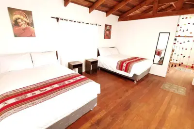 two beds in a room with wooden floors at APARMENT SAMANA HOUSE OLLANTAYTAMBO in Ollantaytambo