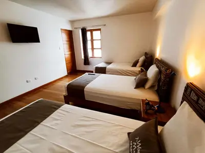 a hotel room with two beds and a flat screen tv at 7th Wonder Apart Hotel Cusco in Cusco