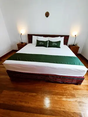 a bedroom with a large bed with two green pillows at 7th Wonder Apart Hotel Cusco in Cusco