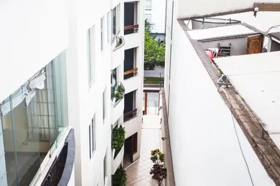 an alley between two buildings with a man standing on the balcony at Beautiful Penthouse in Lima, in front of the park in Lima
