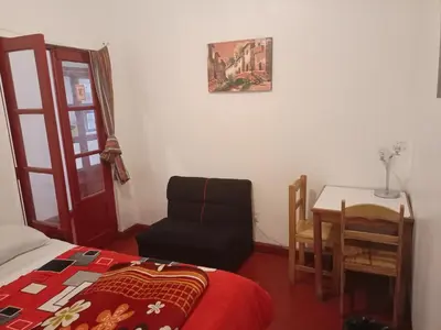 a bedroom with a bed and a chair and a table at SK Hostal in Cusco