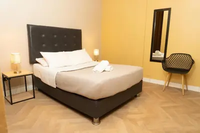 a bedroom with a bed with white pillows and a chair at Wild Rover Huacachina in Ica