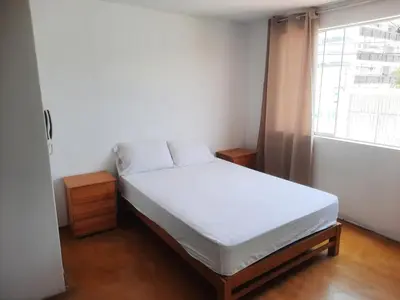 a bedroom with a white bed and a window at Hospedaje Kaihalulu in Punta Hermosa