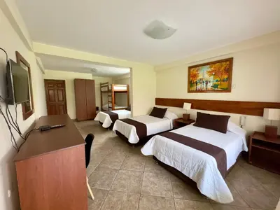 a hotel room with three beds and a flat screen tv at Rio Lindo Ecolodge in Lunahuaná