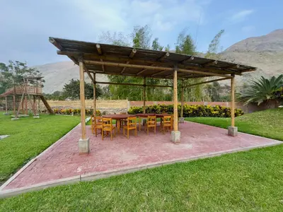a pavilion with a table and chairs in a field at Rio Lindo Ecolodge in Lunahuaná