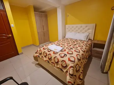 a bedroom with a large bed with yellow walls at Hostal Tuki Huancayo in Huancayo