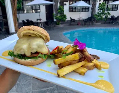 a sandwich and french fries on a plate next to a pool at Hotel Sol de Ica in Ica