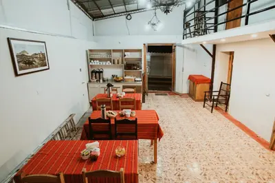 a room with tables and chairs and a kitchen at Cochito Cusco in Cusco