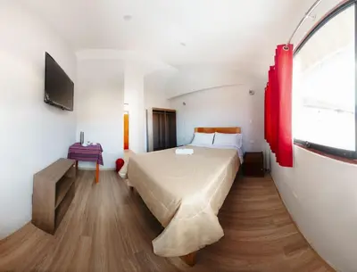 a bedroom with a bed and a red window at Cochito Cusco in Cusco