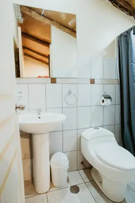 a white bathroom with a sink and a toilet at Cochito Cusco in Cusco