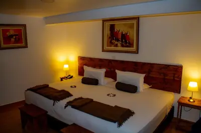 a bedroom with a large white bed with two lamps at Hotel Tara Machupicchu in Machu Picchu