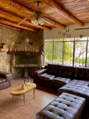 a living room with leather furniture and a stone fireplace at Las Cabañas de Incahuasi in Lunahuaná