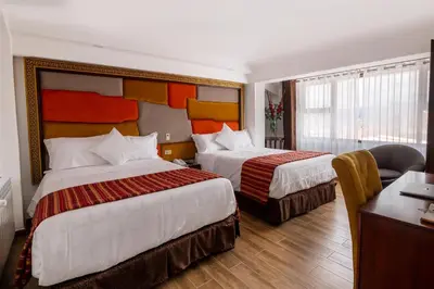 a hotel room with two beds and a desk at Hotel Hacienda Cusco Centro Historico in Cusco