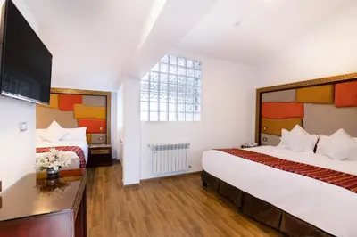 a hotel room with two beds and a flat screen tv at Hotel Hacienda Cusco Centro Historico in Cusco