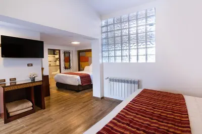 a hotel room with two beds and a flat screen tv at Hotel Hacienda Cusco Centro Historico in Cusco