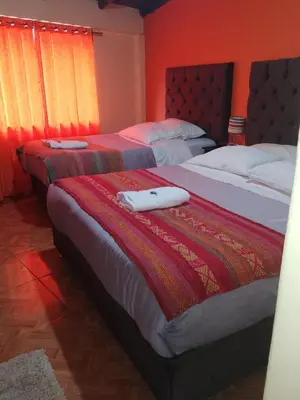 two beds in a bedroom with red walls at hostal Qorisonqo inn ollantaytambo in Ollantaytambo