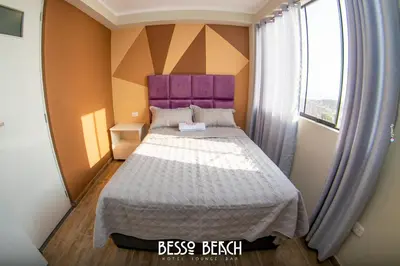 a bedroom with a bed with a purple headboard and a window at Besso Beach Hotel in Barranca