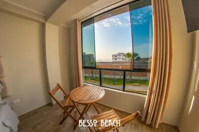 a room with a large window with a chair and a table at Besso Beach Hotel in Barranca
