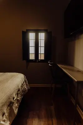 a bedroom with a desk and a bed and a window at Kokoa Hotel Cusco in Cusco