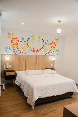 a bedroom with a bed with a painting on the wall at Platero Hotel in Ayacucho
