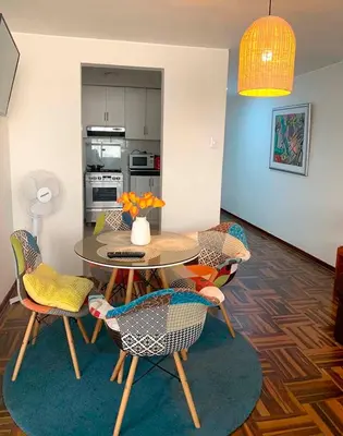 a dining room with a table and chairs and a kitchen at Lindo departamento en Magdalena del Mar in Lima