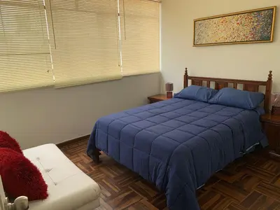 a bedroom with a blue bed and a couch at Lindo departamento en Magdalena del Mar in Lima