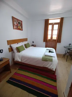 a bedroom with a large white bed and a window at Qente Wings in Ollantaytambo