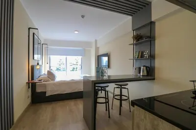 a room with a bed and a kitchen with stools at Grau by Wynwood House in Lima
