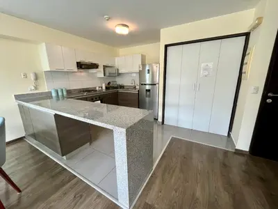 a kitchen with white cabinets and a granite counter top at Elegante Duplex Cerca Parque Kennedy Miraflores in Lima