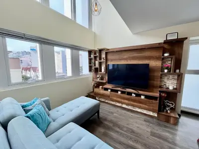 a living room with a blue couch and a flat screen tv at Elegante Duplex Cerca Parque Kennedy Miraflores in Lima