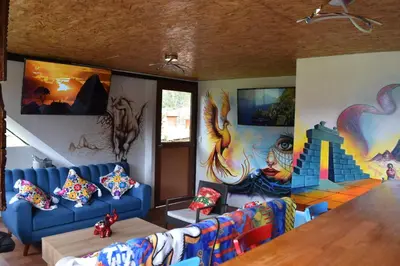 a living room with a blue couch and a mural at New Experiences Valle sagrado in Urubamba