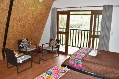 a bedroom with a bed and two chairs and a balcony at New Experiences Valle sagrado in Urubamba