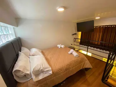 a bedroom with a bed with pillows and a flat screen tv at Loft en centro histórico Cusco Inlove in Cusco